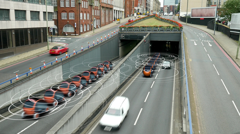 Two rows of self driving car models composited onto a real urban road.
