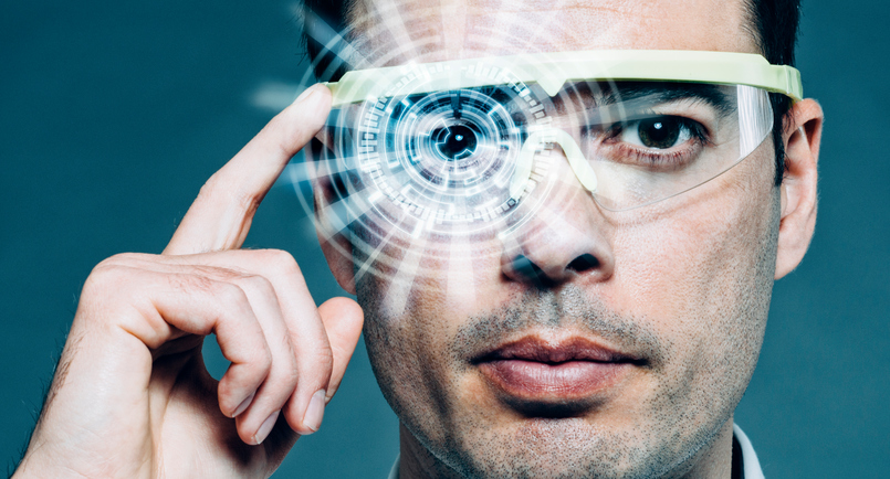 Man wears a pair of futuristic glasses which he adjusts with one finger. In front of his eye is a heads-up display (HUD) that shows lots of data like numbers and structures. It is a concept of augmented reality or a hologram.