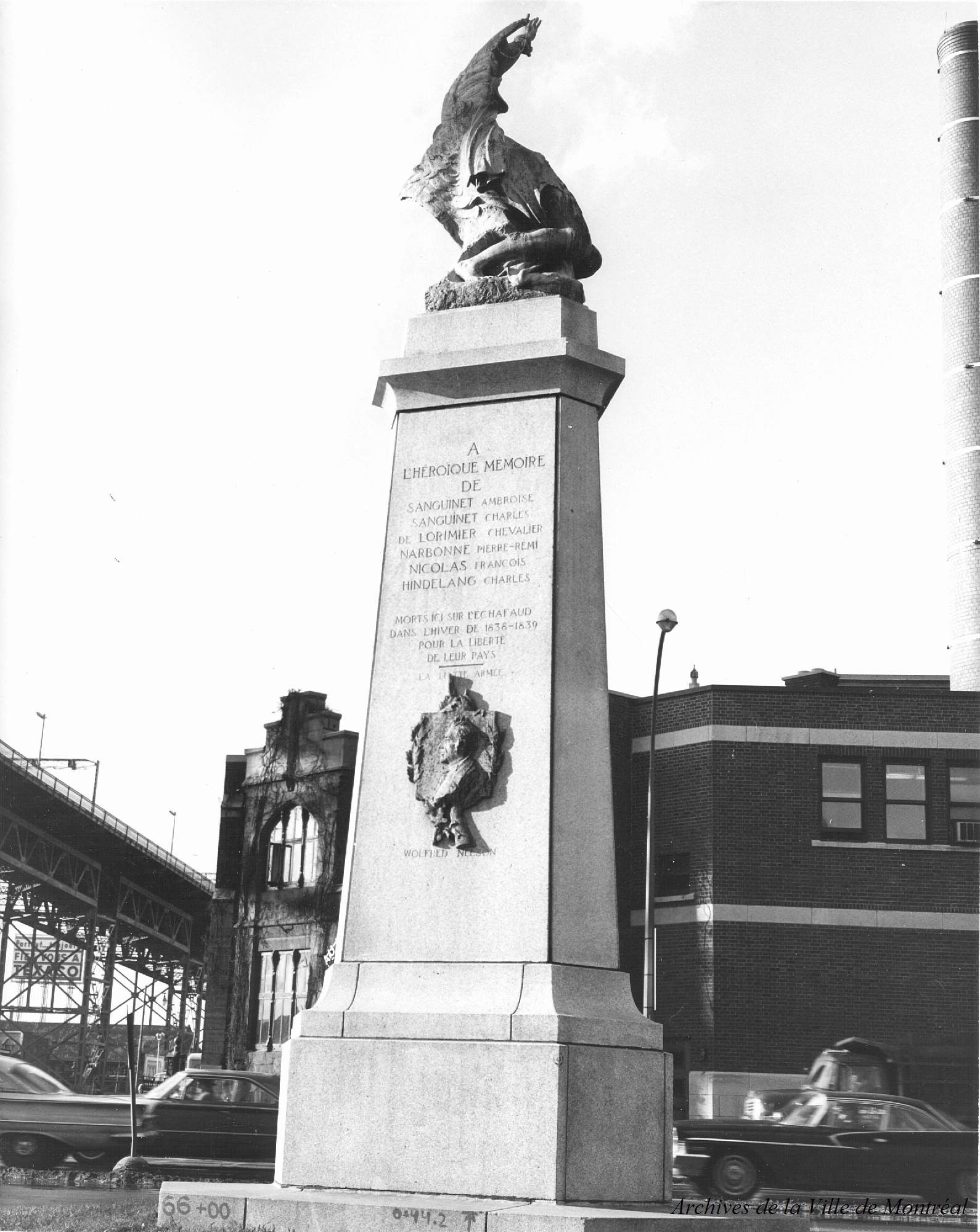 Photo du monument aux Patriotes avec le pont et la prison en arrière-plan.