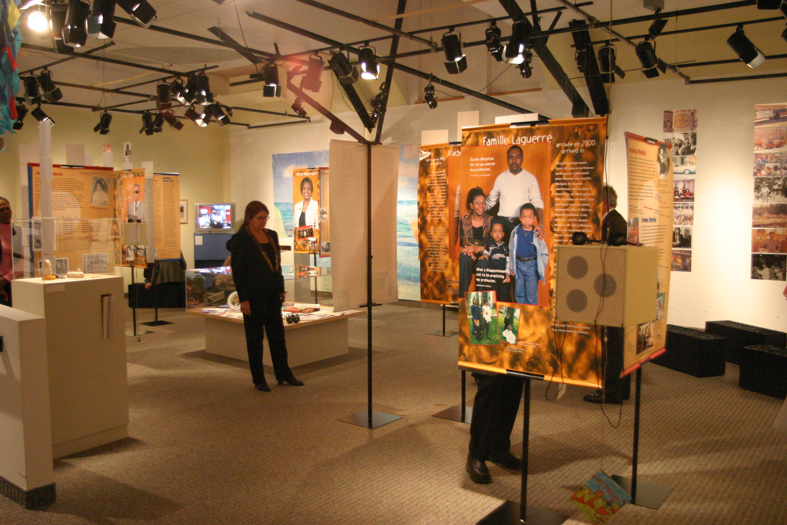 Photo couleur d’une salle d’exposition avec des bannières sur pied et quelques visiteurs..