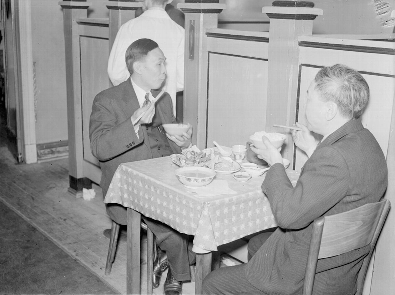 Deux hommes mangent du Chop Suey dans le Quartier chinois.