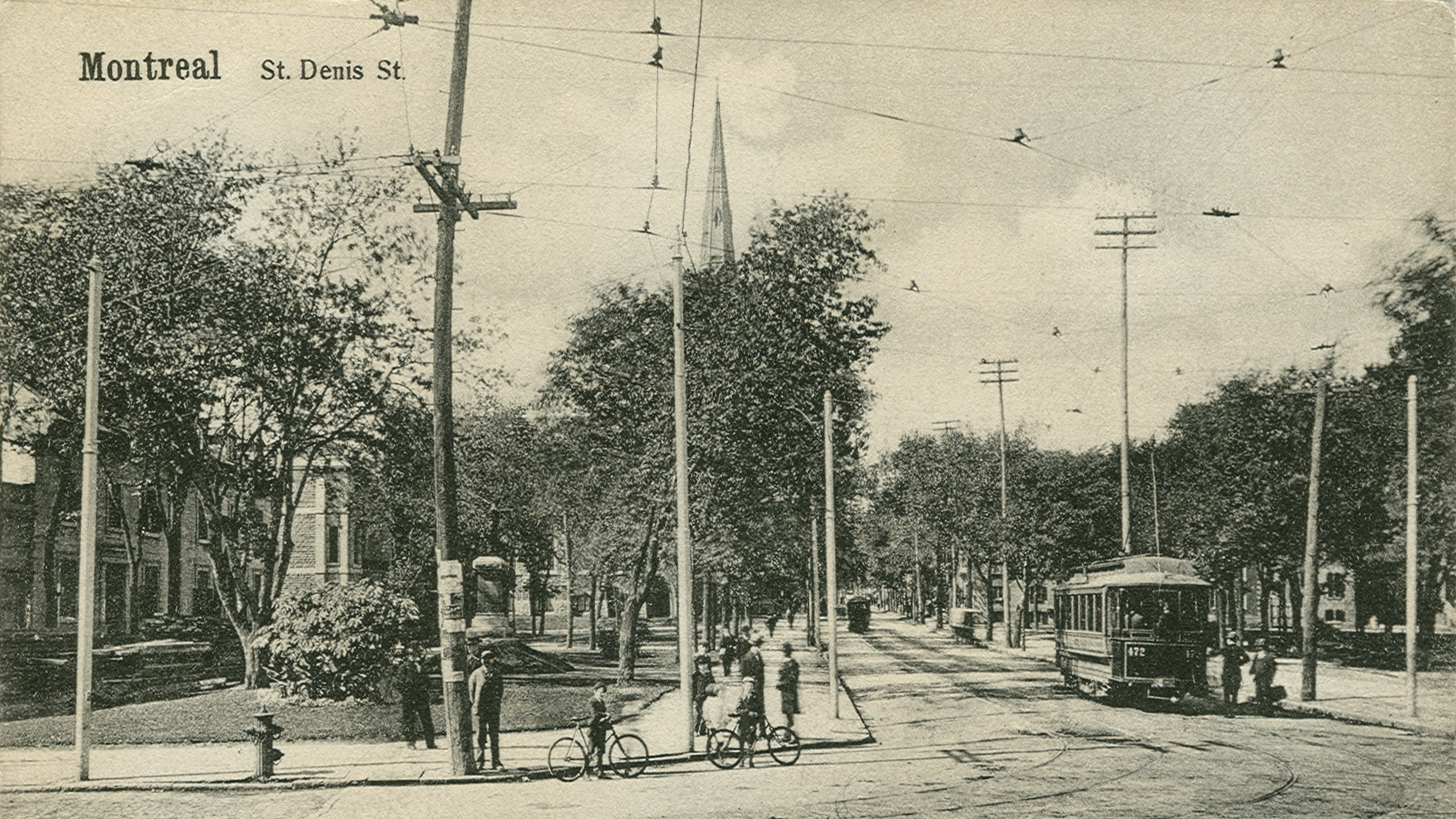 Scène de rue, avec deux jeunes cyclistes et un tramway.