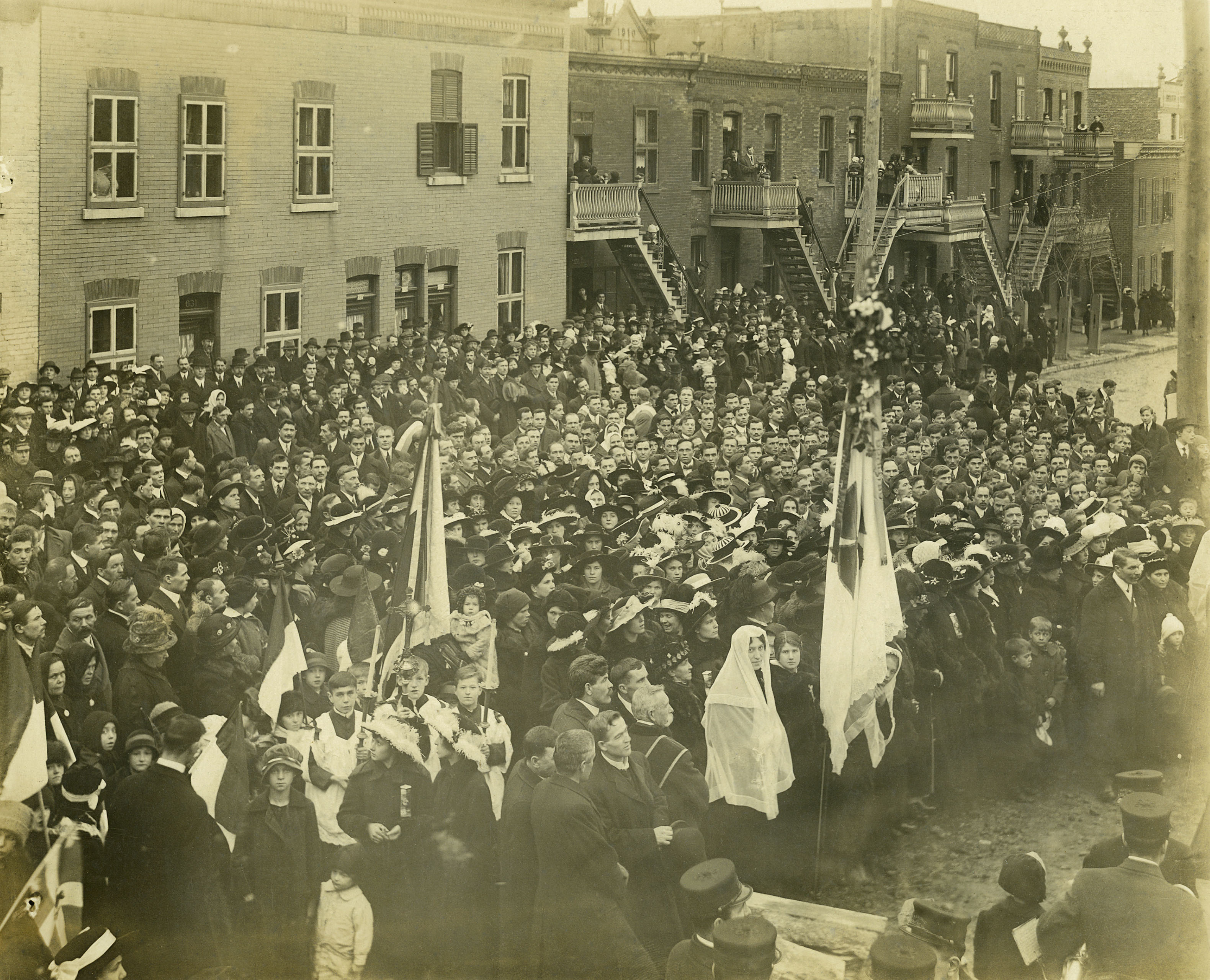 En 1917, lors de la bénédiction de l’église paroissiale Saint-Michel, les fidèles se réunissent devant l’église, rue D’Iberville. 