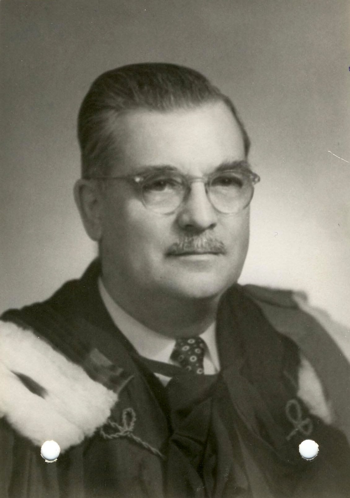 Photo en plan buste d’un homme portant des lunettes et une moustanche.