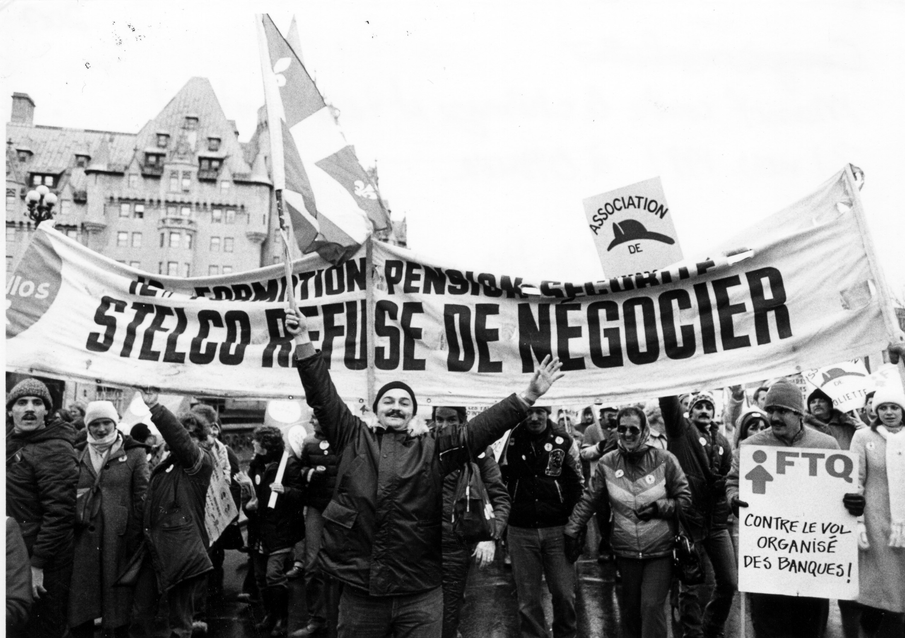 Des travailleurs manifestent en brandissant une banderole portant l'inscription "Formation - Pension - Sécurité LA STELCO REFUSE DE NÉGOCIER".