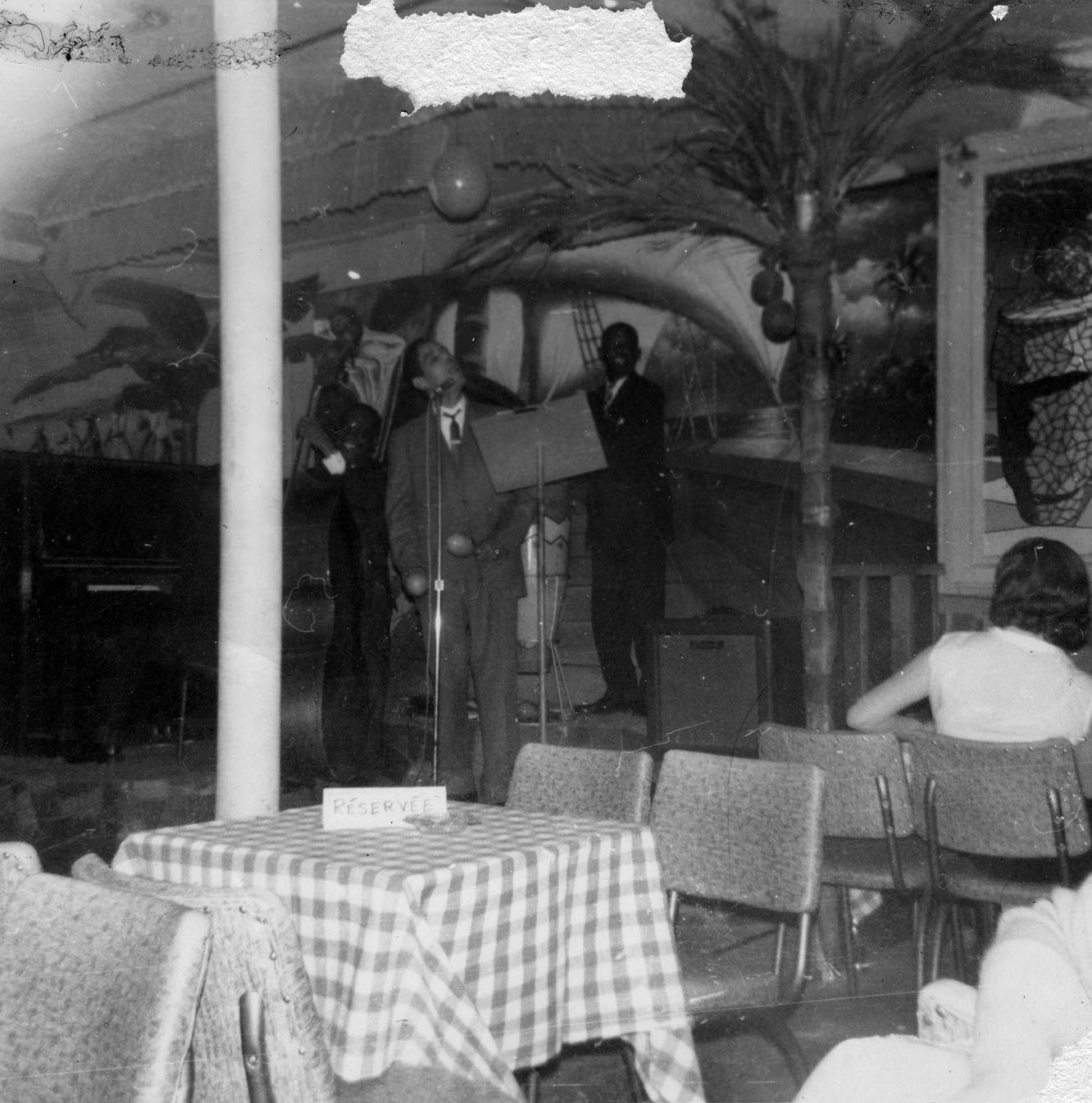 Deux musiciens et un chanteur sur une petite scène dans un café