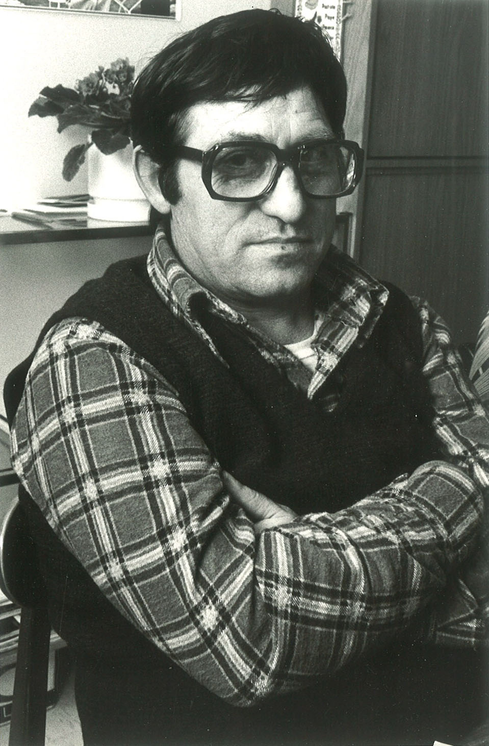 Photo d'un homme portant des lunettes, les bras croisés
