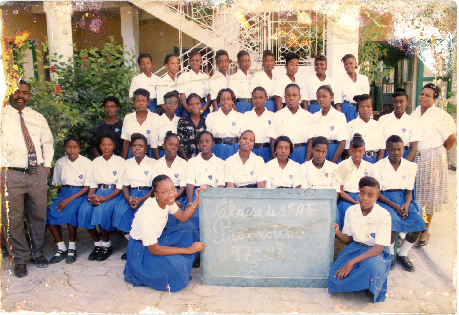 Photo de classe de jeunes filles portant une chemise blanche à manches courtes et une jupe bleue. 