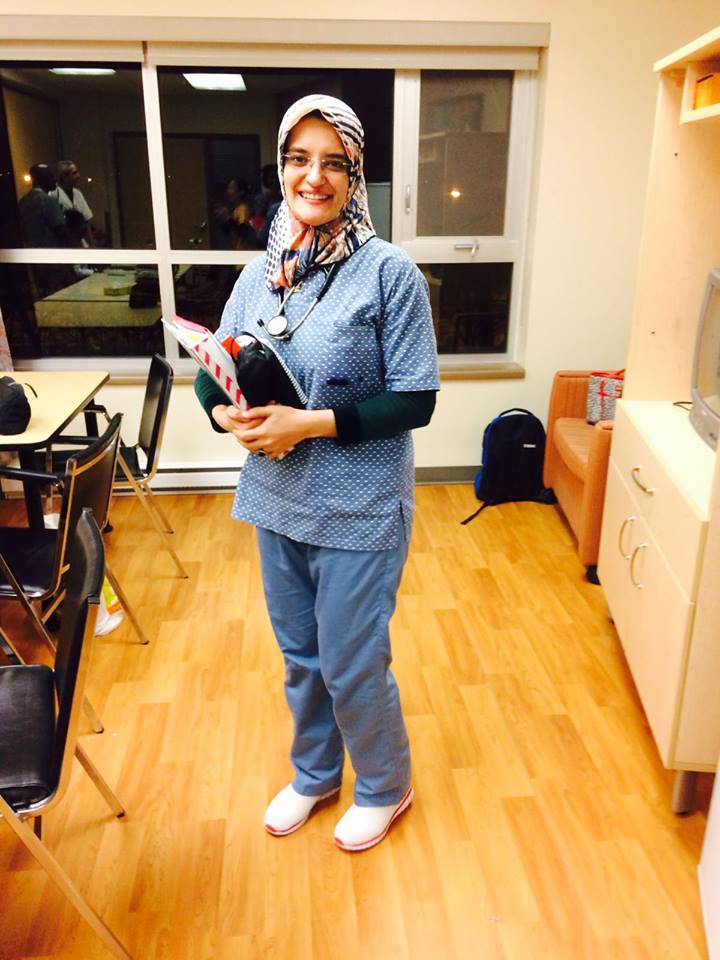 Photo plein pied d’une infirmière avec un stéthoscope autour du cou et tenant un cartable et différents objets.