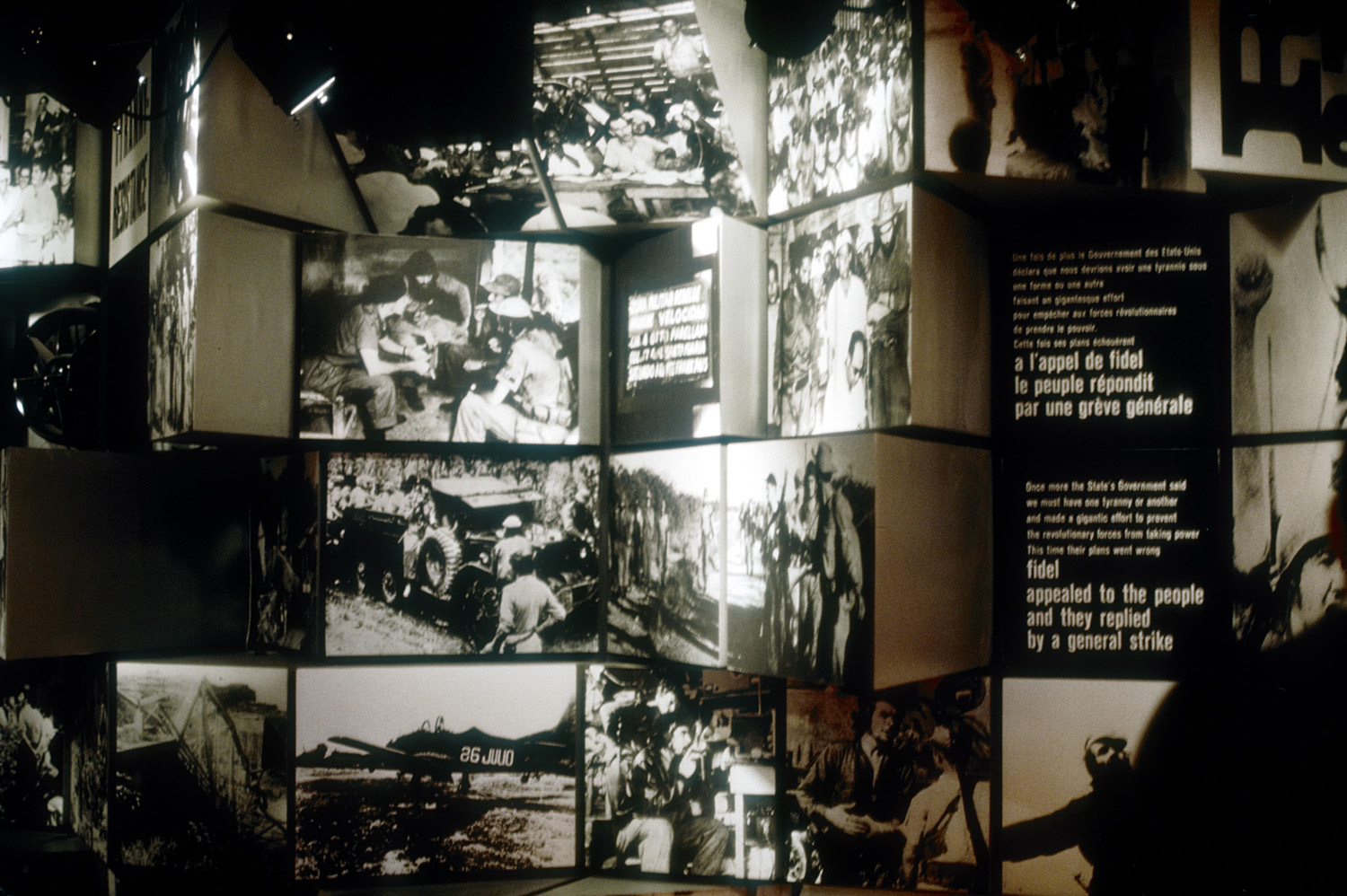Des photographies représentant différents moments de la révolution cubaine ornent un mur aux faces irrégulières.