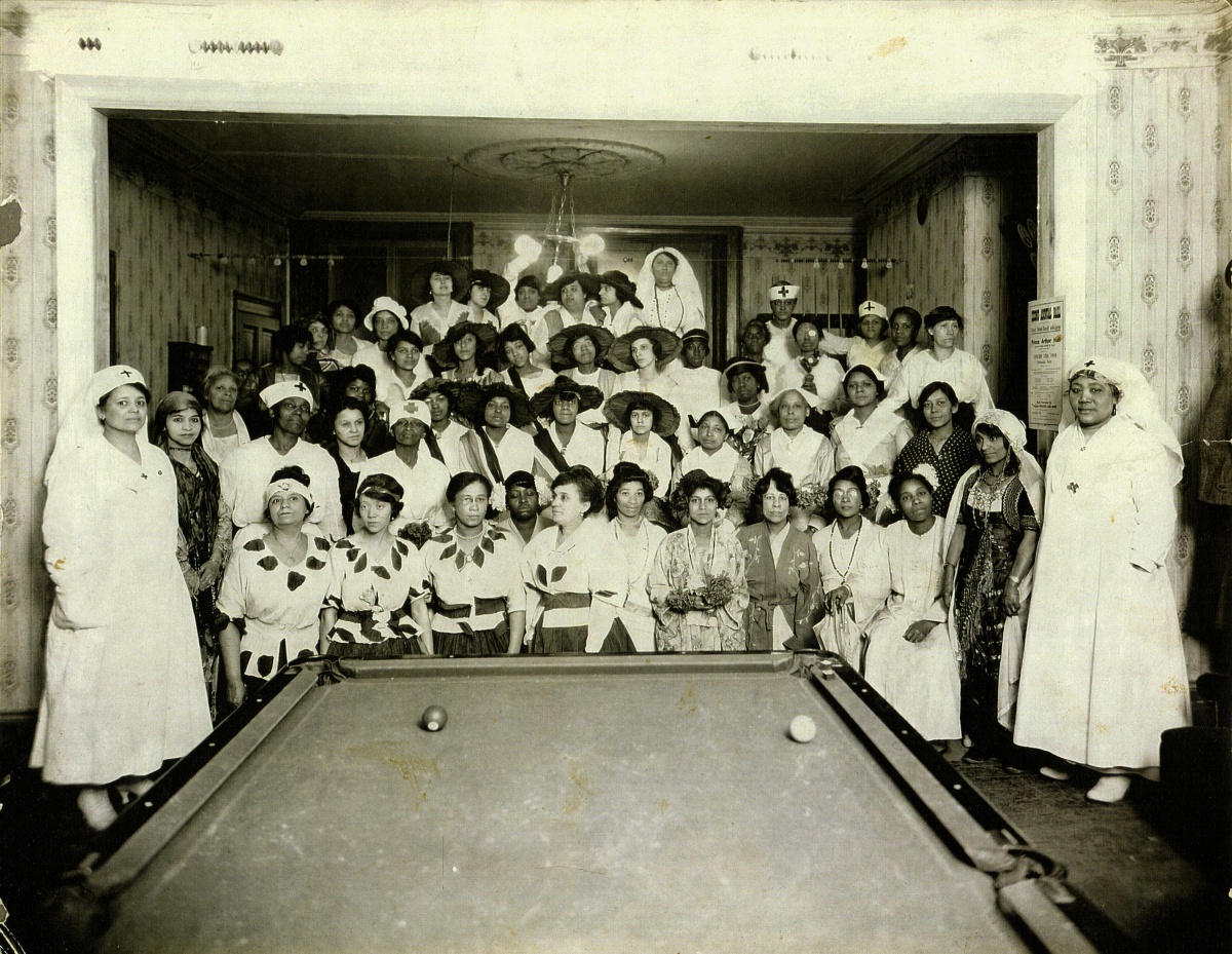 Un groupe d'une cinquantaine de femmes noires posent pour le photographe dans une salle où l'on voit une table de billard en avant-plan.