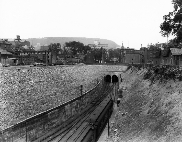 Photographie de la sortie du tunnel avec des bâtiments autour et le mont Royal en arrière-plan.