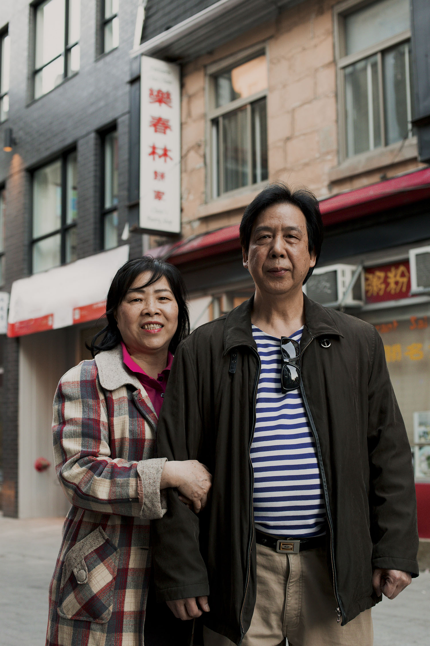 Colour photo of a woman and a man standing next to each other in front of a building in Montréal’s Chinatown.