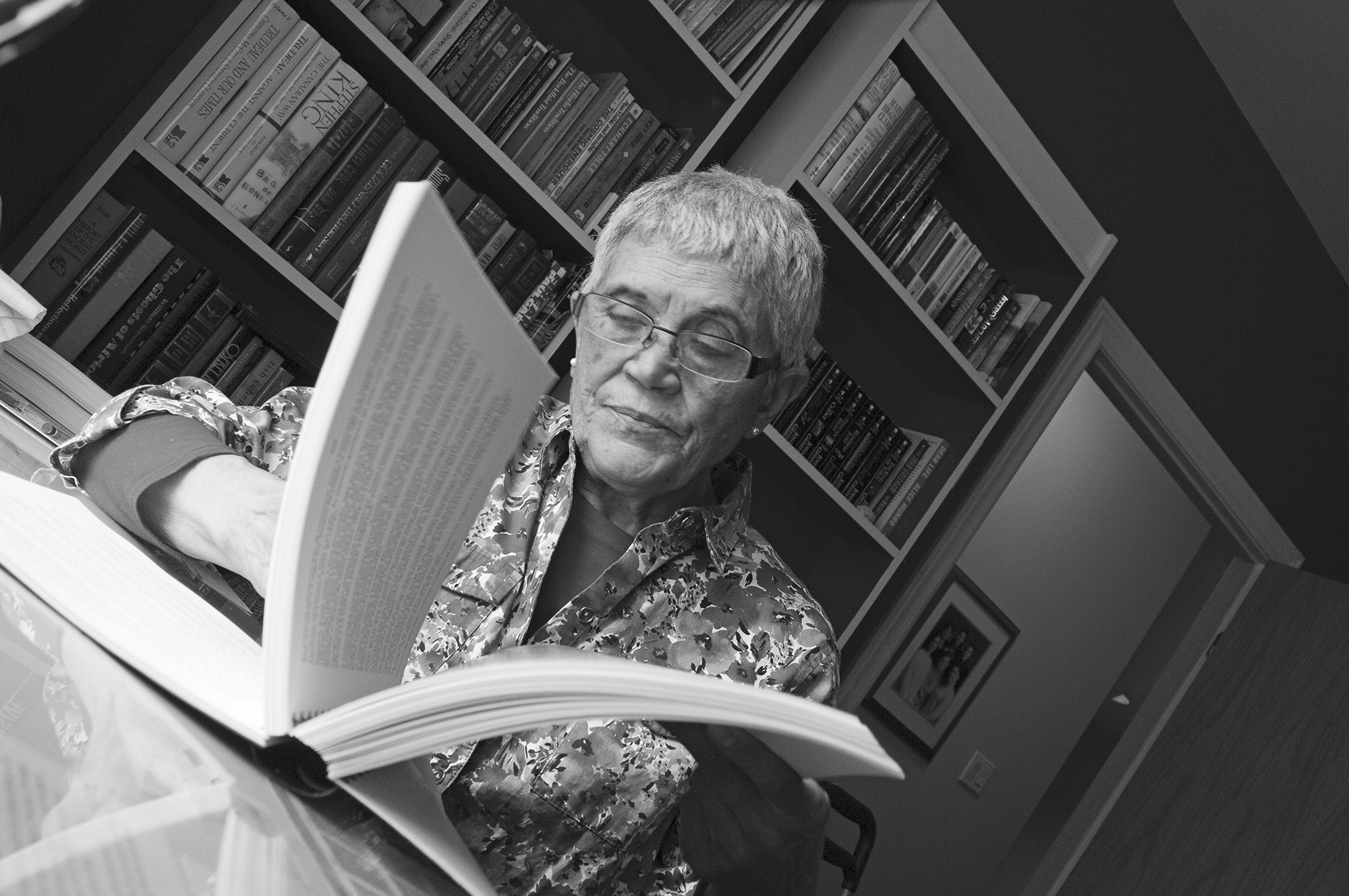 Photo en noir et blanc montrant une femme en plan rapproché tournant les pages d’un cahier.