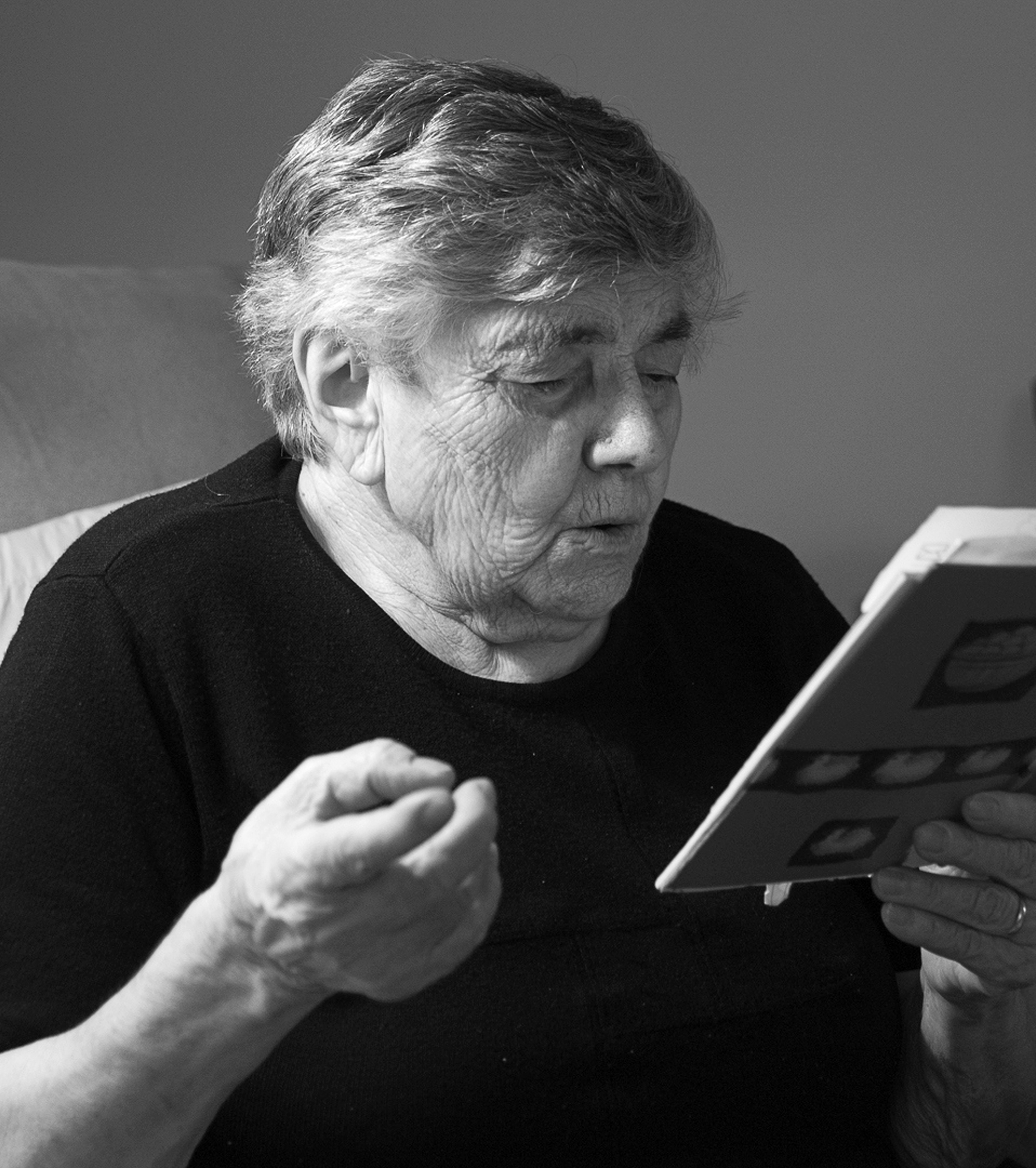 Photo en noir et blanc montrant une grand-mère et tenant un livre en plan rapproché.
