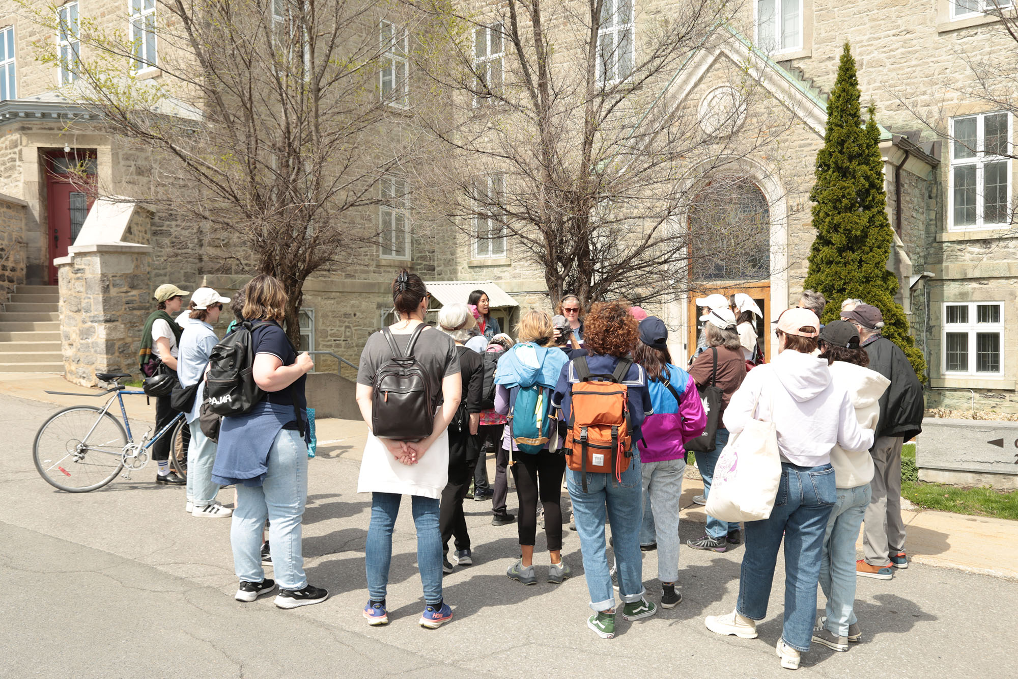 Personnes regroupées suivant une visite guidée extérieure devant un bâtiment historique.