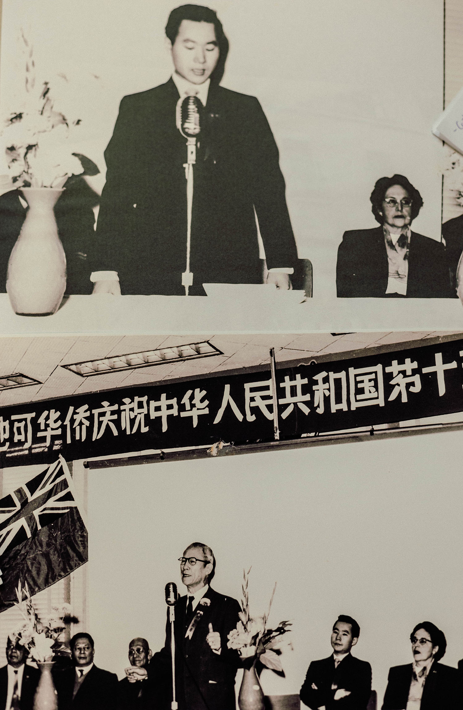 Cette image montre deux photos en noir et blanc. Celle du haut montre un homme d’origine chinoise debout derrière une table, un micro devant lui, et une dame assise à ses côtés. Celle du bas un homme debout au micro et de chaque côté des hommes assis.
