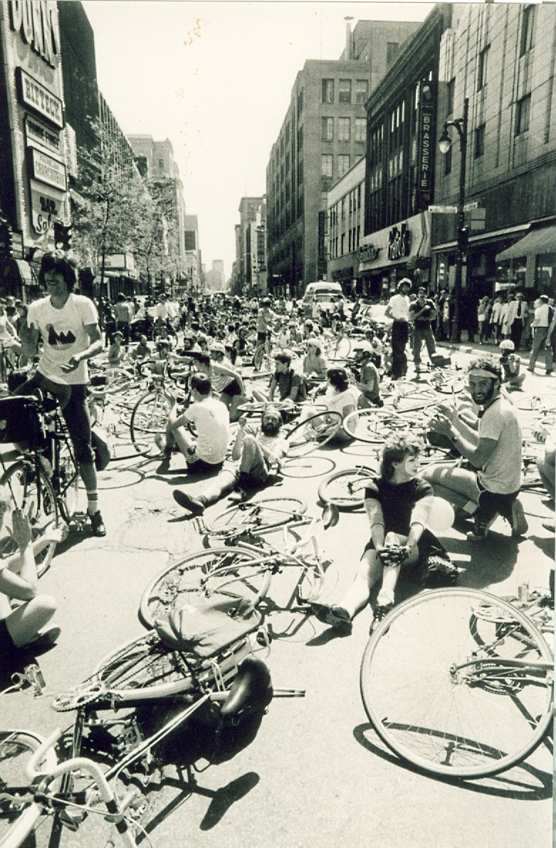 Manifestation de cyclistes sur la rue Sainte-Catherine. Les vélos et les cyclistes sont sur le sol. 