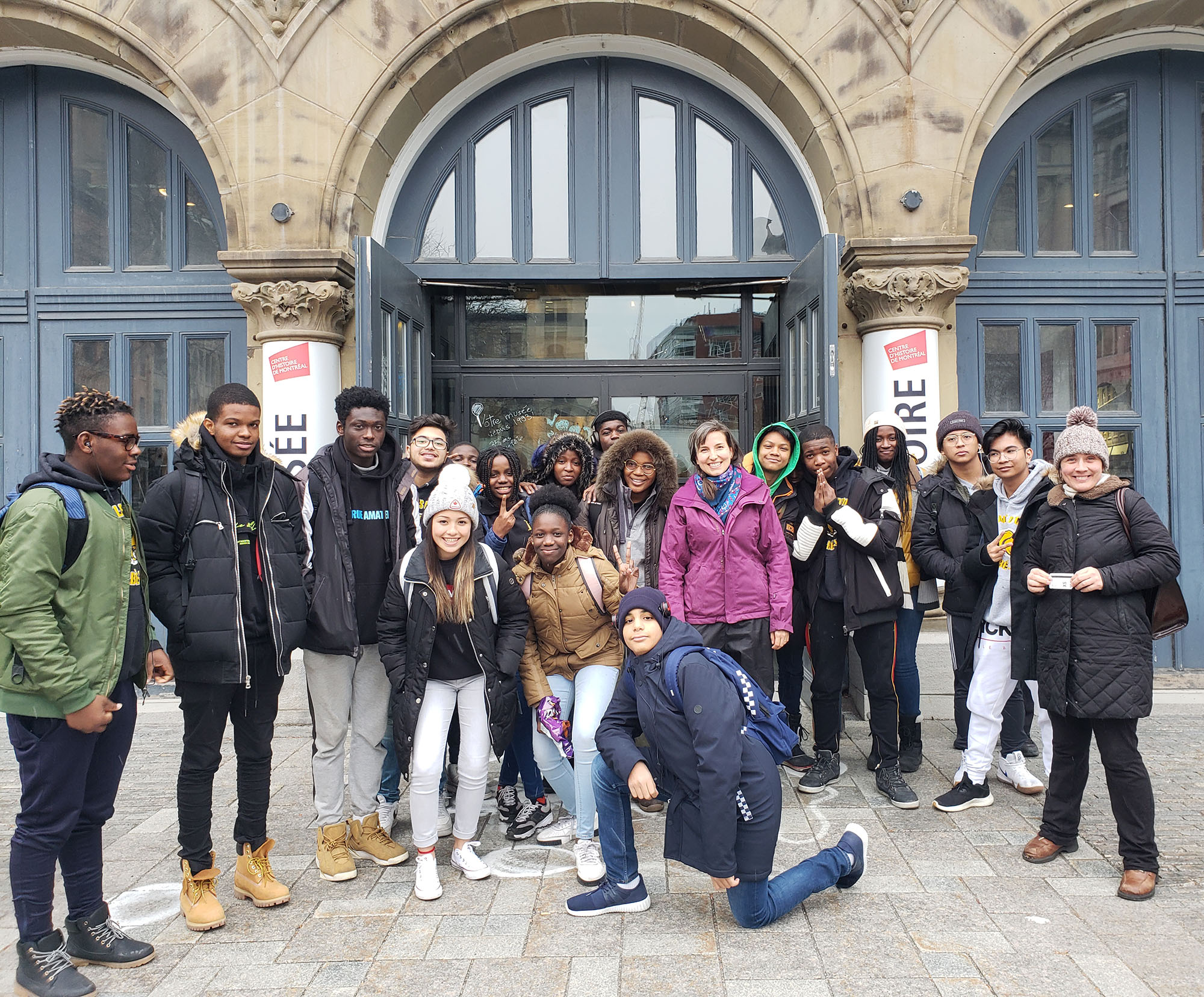 Dix-sept élèves et deux enseignantes prennent la pose devant le Centre d’histoire de Montréal. 