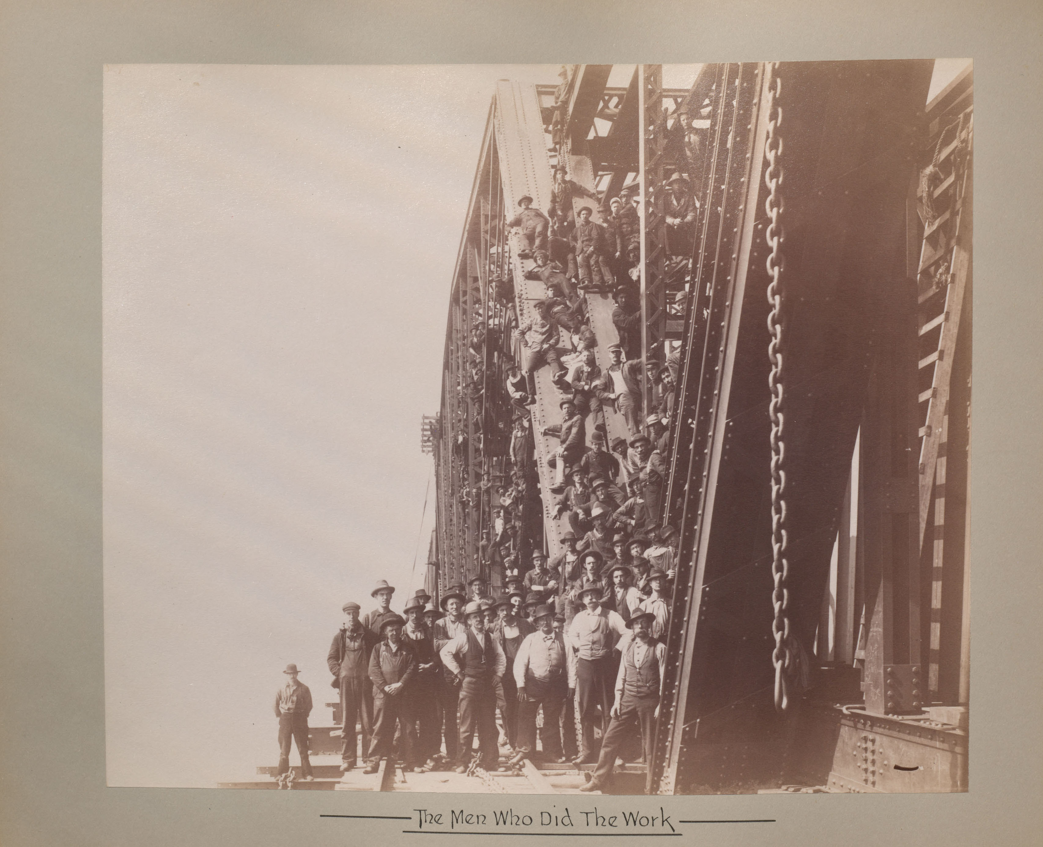 Les hommes qui ont travaillé à la construction du pont posent devant et sur la structure métallique du pont.