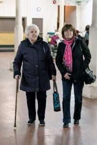 Une femme marche appuyée sur une canne. Une autre femme plus jeune est à ses côtés.