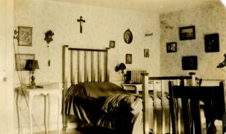 Chambre à coucher meublée d’un lit à une place, de deux tables de chevet, de deux lampes et de décorations murales.