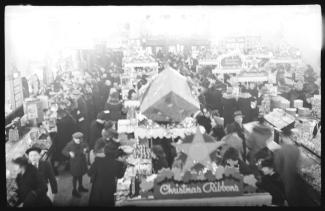 Des dizaines de jeunes et d’adultes circulent dans un grand magasin où l’on voit de nombreuses décorations au-dessus des étalages. 