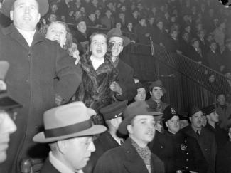 Nous voyons des spectateurs d'un match de hockey opposant le Canadien de Montréal aux Red Wings de Détroit. Ce match est présenté au Forum de Montréal