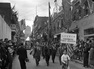 Le 2 septembre 1945, le défilé de la Victoire parade sur la rue De La Gauchetière Ouest dans le Chinatown. En avant-plan, un petit garçon porte une pancarte de l’association Chinese Free Mason. 