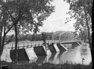 Photo en noir et blanc d’un pont métallique, d’une rive à l’autre.