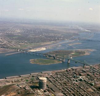 Vue aérienne en couleur montrant au centre le fleuve Saint-Laurent et le pont Jacques-Cartier, avec une partie des rives de Montréal et de la Rive-Sud.