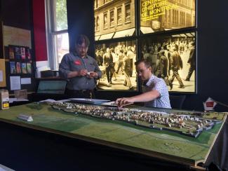 Deux employés du Centre d'histoire travaillent sur la maquette de Montréal en 1745