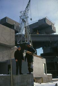 Deux ouvriers et une grue sur le chantier de construction du complexe Habitat 67.