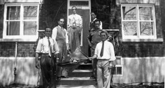 Six Açoriens posent devant une maison en tenant un drapeau. 