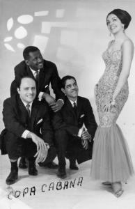 Trois hommes accroupis regardent une femme en robe de soirée à leur côté