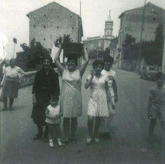 Trois femmes, un garçon et un enfant prennent la pose au milieu d'une rue d'une petite ville italienne