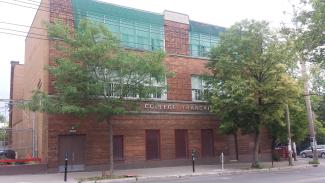 Photographie contemporaine d’un bâtiment de brique de trois étages. 