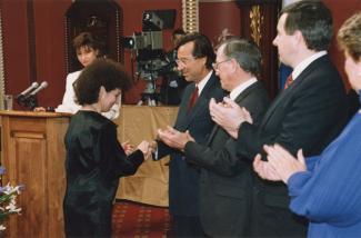 Aoura Bizzarri reçoit des mains du premier ministre Robert Bourassa la médaille de l’Ordre national du Québec à l'Assemblée nationale.