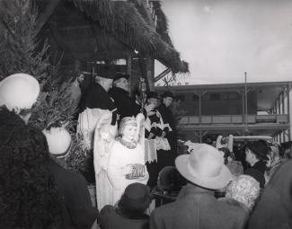 Aux côtés de quatre ecclésiastiques, monseigneur Paul-Émile Léger donne sa bénédiction sur les ondes de CKAC de la crèche extérieure de l’Oratoire le 25 décembre 1950. Près de la scène, plusieurs personnes et un petit ange mécanique.