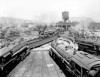 Photographie en noir et blanc de la rotonde Turcot. En arrière-plan, la falaise Turcot et l’immeuble du 780, rue Saint-Rémi derrière la tour d’eau de la gare de triage Turcot. 