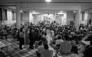 Photo noir et blanc d’un rassemblement de femmes dans le gymnase d’une ancienne école.