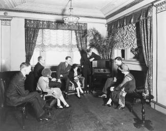 Groupe de personnes réunies autour d’un récepteur radio dans les années 1920.