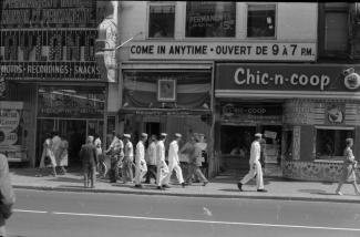 Photo noir et blanc montrant des marins et des passants déambulant rue Sainte-Catherine Ouest dans les années 1950.