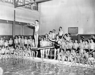 Groupe de jeunes hommes, du moniteur et de deux prêtres autour d'une piscine.