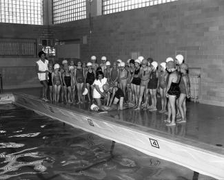 Groupe de jeunes filles autour de la piscine, assistant au cours de sécurité aquatique.