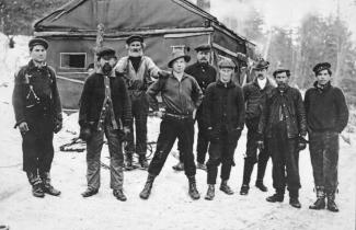 Photo noir et blanc de neuf hommes dans un camp de bûcherons en hiver