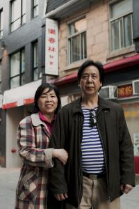 Photo couleur d’une femme et d’un homme se tenant debout collés l’un contre l’autre devant un édifice dans le quartier chinois.