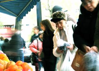 Des gens circulent et regardent les fruits sur un étal sur le trottoir du Quartier chinois