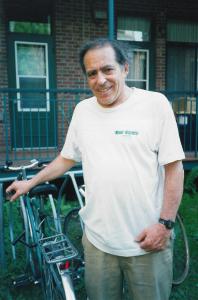 Robert Silverman accoudé à son vélo et portant un t-shirt du Monde à Bicyclette