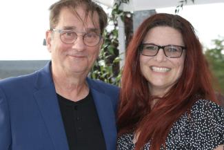 Photo couleur d’un homme et d’une femme qui sourient en gros plan. Tous deux portent des lunettes.